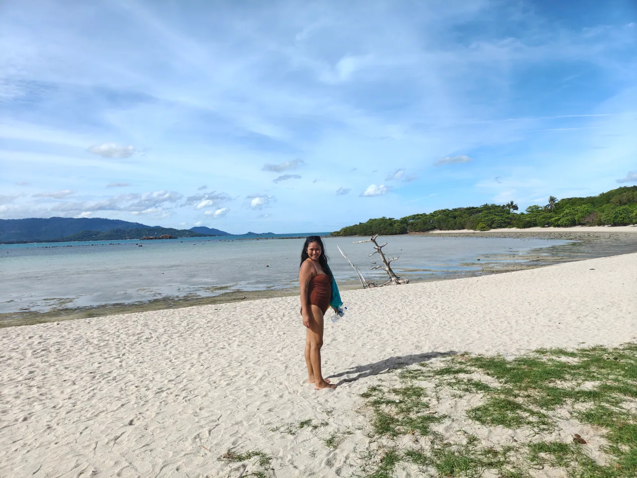 A visitor on a stretch of sandy beach beside the sea on Koh Madsum